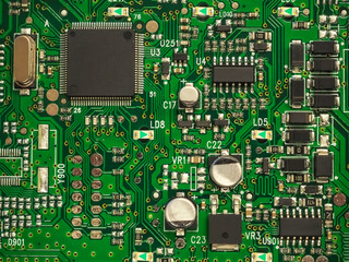 Close-up of electronic circuit board PCB with components: microchip, processor, integrated circuits, capacitors, resistances and electronic connections are noted. High-quality macro photography.