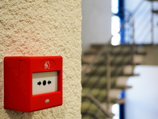 Close-up of the red manual Fire Call Point mounted or installed in the landing on a yellow wall. High-quality macro photography.