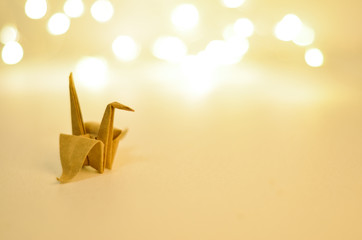 Paper origami crane on background with blurred lights. Soft selective focus.
