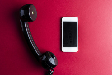 Vintage telephone handset vs smarphone on red - 199044727