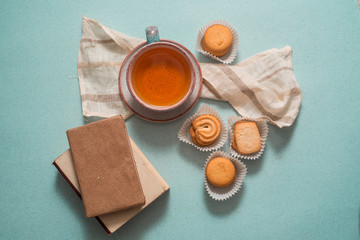 tea in a clay blue cup with a saucer, miscellaneous cookies, old small books on a blue background...