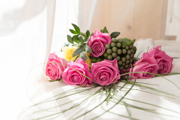 Bouquet of pink roses on white bed and balloons background