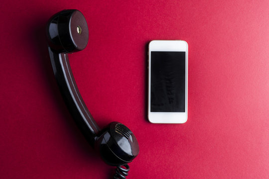 Vintage telephone handset vs smarphone on red