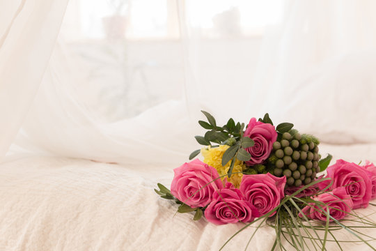 Bouquet of pink roses on white bed and balloons background