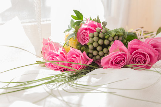 Bouquet of pink roses on white bed and balloons background