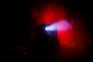 Old style movie projector, close-up. Film projector on a wooden background with dramatic lighting and selective focus. Movies and entertainment concept