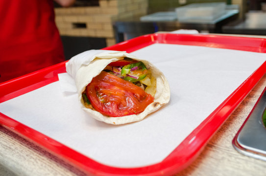Shawarma meat chicken roll in a pita with fresh vegetables.