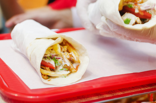Shawarma meat chicken roll in a pita with fresh vegetables.