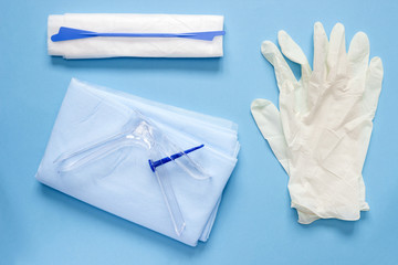 An overhead photo of the vaginal speculum, napkin, medicine gloves and spatula. The medical tools for holding open the vagina during medical investigation. Feminine woman health diagnosis.