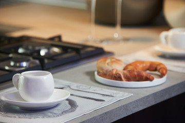 Delicious croissant and a two cup of coffee on a kitchen counter. Healthy breakfast with coffee in sunny morning for two person in modern kitchen interior