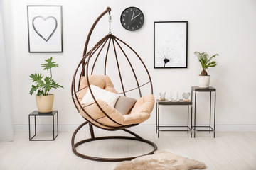 Tropical plants with green leaves and swing chair in room interior