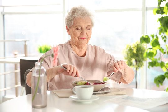Elderly woman having breakfast at home