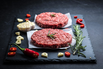 Raw cutlet of minced meat with ingredients on a dark cooking background