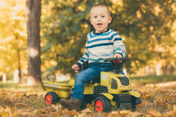 Boy driving a toy truck in park outdoors