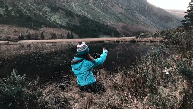 woman photographer taking photos near the lake in mountains