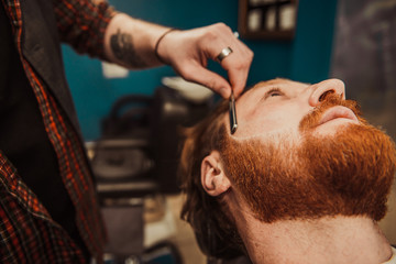 Professional Master hairdresser cuts client beard.