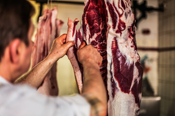 Fototapeta na wymiar butcher cut raw meat with a knife at table in the slaughterhouse