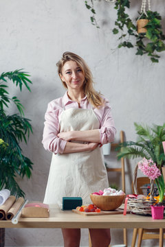 Photo of florist woman in apron at room with flowers