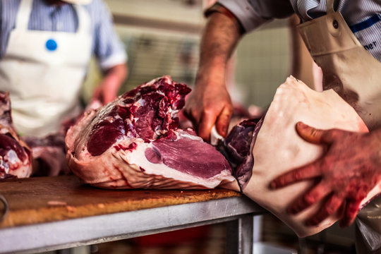 butcher cut raw meat with a knife at table in the slaughterhouse