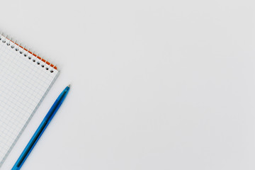 Top view of an open spiral blank notepad with a pen on a white table background