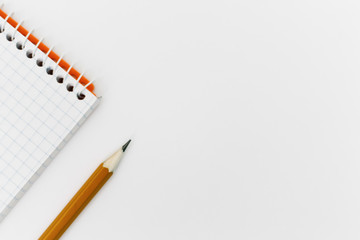 Top view of an open spiral blank notepad with a pencil on a white table background