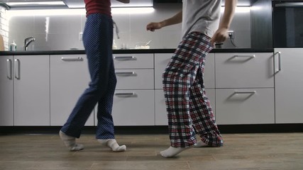 Legs of happy couple in pajamas listening to music and dancing together in the kitchen. Positive boyfriend and girlfriend dancing and having fun after they woke up in the morning in good mood