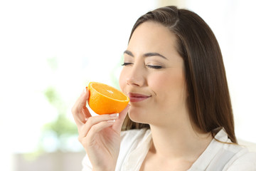 Pretty woman smelling half orange at home