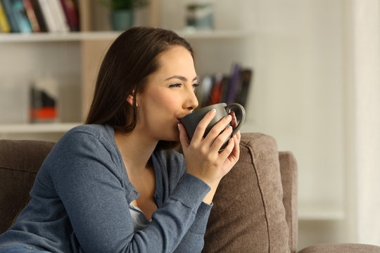 Relaxed happy woman drinking coffee at home