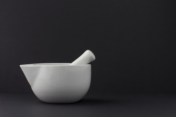 white porcelain mortar and pestle set on black background