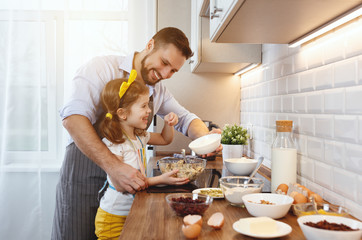 happy family in kitchen. Father and child daughter knead dough and bake biscuits .