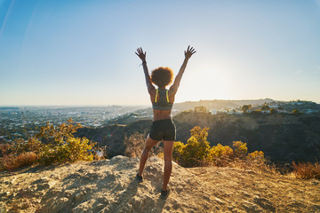 athletic african american woman celebrating reaching top of runyon canyon with arms open - obrazy, fototapety, plakaty