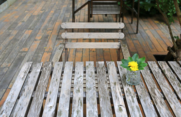Vintage style wooden table and chair in the garden with glass of flower decoration.