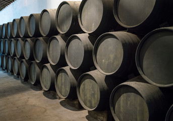 Row of stacked wooden wine barrels for sherry aging