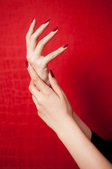 Hands with long nails and nail polish on a red background