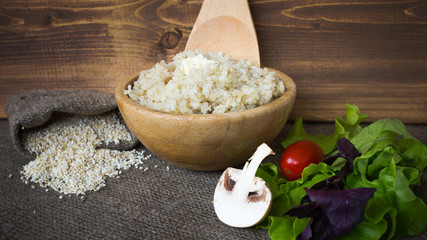 Barley groats in a bowl. A baggie of dry cereal and vegetables (mushrooms, tomato, red basil herb leaves, green salad) on rustic background.