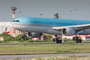 Fototapeta na wymiar Closeup of modern passenger airplane landing with touchdown on the runway at the airport in summer, side view