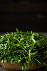 Fresh rucola with water droplets on a dark rustic background