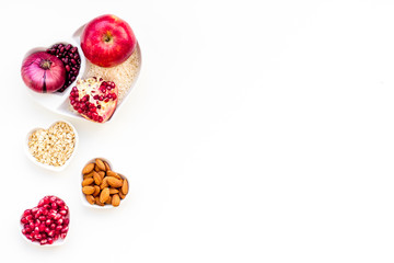 Diet for healthy heart. Food with antioxidants. Vegetables, fruits, nuts in heart shaped bowl on white background top view copy space