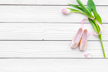 Ballet shoes near delicate flowers on white wooden background top view copy space