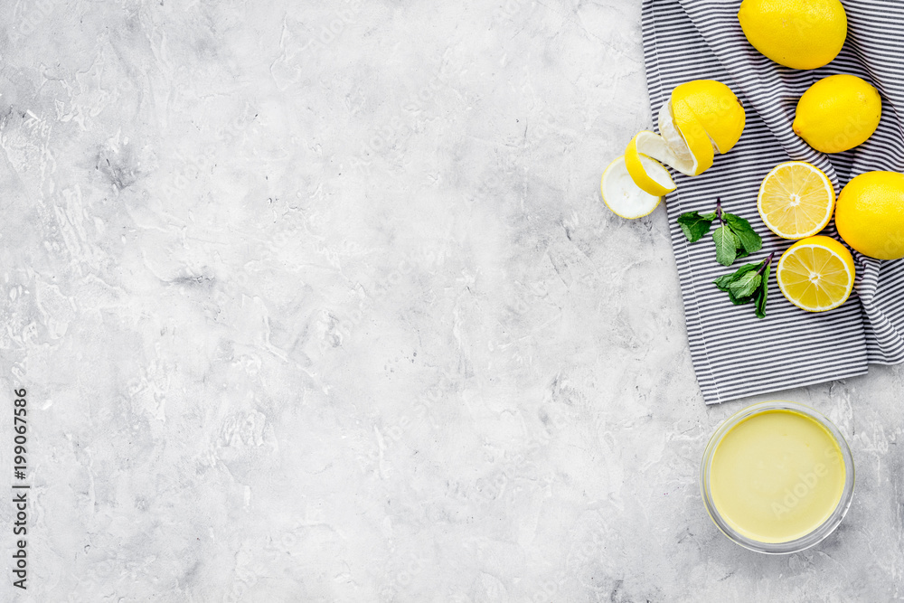 Wall mural Lemon curd in bowl among lemons on grey background top view copy space