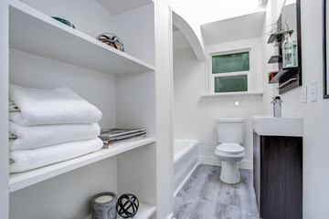 Narrow white bathroom interior with open shelves