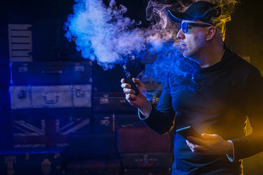 A man smokes an electronic cigarette. bearded man vaping. Men with beard in sunglasses vaping and releases a cloud of vapor.