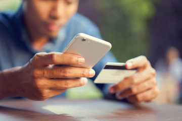 close up teenager man hand holding smartphone and trying to paying by credit card:shopping online...