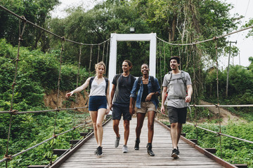 Group of friends walking on the bridge in a tropical countryside adventure and journey concept - obrazy, fototapety, plakaty