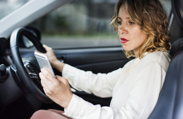 Fototapeta na wymiar Woman using mobile phone while driving