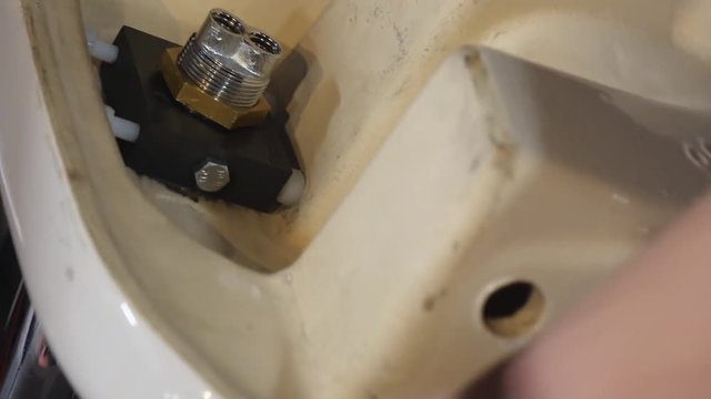 Close up shot of man's hands holding sink on the floor or table or and fixing water mixer tap to it using ratchet socket wrench and a spanner