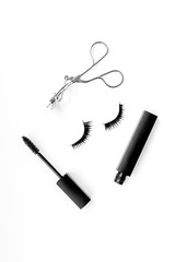 Cosmetics and tools for voluminous lashes. Mascara, false eyelashes, eyelash curler on white background top view space for text