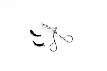 Curled and thick eyelashes. False eyelashes and eyelash curler on white background top view copy space