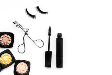 Makeup cosmetics for eyes. Eyeshadow, mascara, false eyelashes, eyelash curler on white background top view copy space