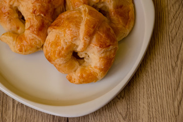 Croissants pastry on the wooden table. The croissants is a bread product made of a layered yeast-leavened dough with butter rolled and folded several times in succession, then rolled into a sheet.